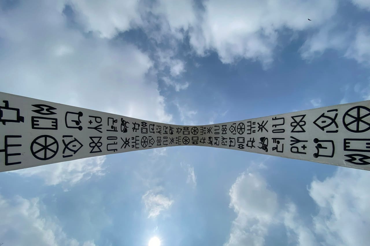 A ribbon printed with rows of care-label style symbols against a cloudy sky